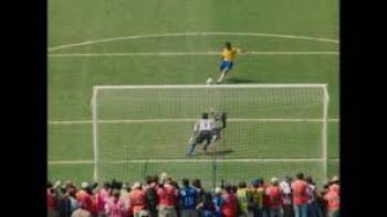 USA 94: Brazil's Return to Glory movie: Soccer player in yellow takes a penalty kick as goalie and crowd watch.