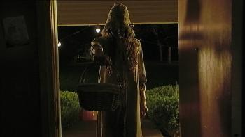 V/H/S/Halloween Movie: A creepy hooded figure stands in a doorway and holds out a basket