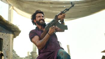 Vikram Vedha: A bearded Indian man fires an automatic rifle into the sky 