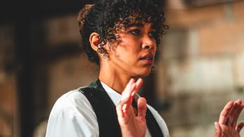 Violent Ends Movie: Eyes brimming with tears, Emma (Alexandra Shipp) raises her hands, as if being held at gunpoint