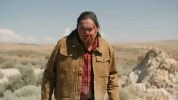 Wardriver movie: William Belleau stands in the desert with blood on his face, peering down at something