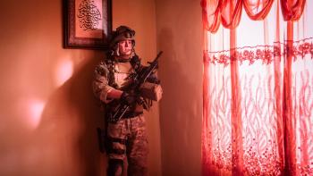 Warfare Movie: Tommy (Kit Connor) waits up against a wall near a window; a colored curtain bathes the room in red