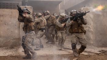 Warfare Movie: Several soldiers, guns pointed at all angles, try to exit a yard surrounded by a concrete wall