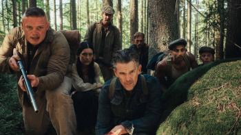 The Weight Movie: Letender holds a rifle as Murphy, Anna, and several others crouch behind a rock, watching something