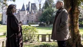 Mr. Blake at Your Service!: An older White woman and man stand looking at each other in the grounds of a castle-like building