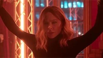 Wildcat: Kate Beckinsale stands with her arms in the air against a neon-lit background