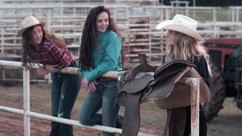 Wildfire: The Legend of the Cherokee Ghost Horse movie: Three teen girls hang over the bars of a riding pen in an empty rodeo arena