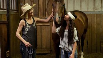 Wildfire: The Legend of the Cherokee Ghost Horse movie: Anne Heche and a teen girl with a bandaged head pet a horse in a stable