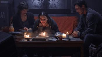 Worldbreaker: Billie Boullet blows out birthday candles next to her mom (Milla Jovovich) and dad (Luke Evans) on a couch in a bomb shelter