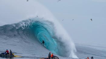 100 Foot Wave TV show screenshot 1: a giant wave towers over surfers