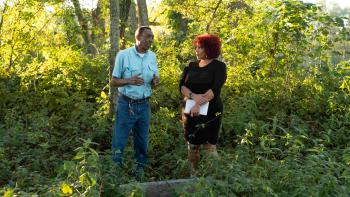  The 1619 Project TV show: Nikole Hannha-Jones talks to someone while standing amongst the trees.