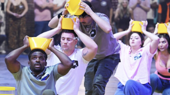 99 to Beat TV show screenshot 3: Contestants carry yellow plastic contains with water on their heads.