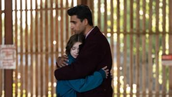 A Good Girl's Guide to Murder: Season 2 TV show screenshot: Man and woman hugging in front of a sunlit fence.