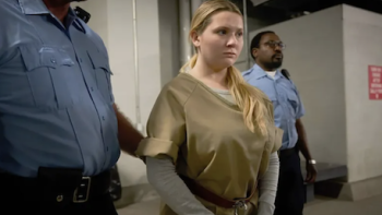Accused TV show screenshot 3: Esme Brewer (Abigail Breslin) in beige jumpsuit led by police in chains. 