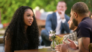 Age of Attraction TV show screenshot 2: A woman with long curly hair talks to man in black shirt. 