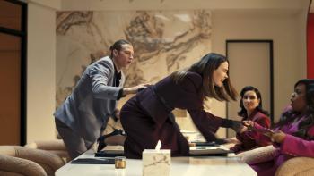 Sarah Paulson, on the table, snatches a folder out of Niecy Nash-Betts hands. Matthew Noszka stands as Kim Kardashian watches.