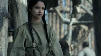 American Primeval TV show screenshot 3: Shawnee Pourier standing outside. She has a scar on her face and wears her hair in two long pigtails.