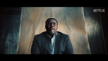 Former quarterback Emmitt Smith speaks to the camera, dramatically lighted while sitting in front of a beige fabric backdrop