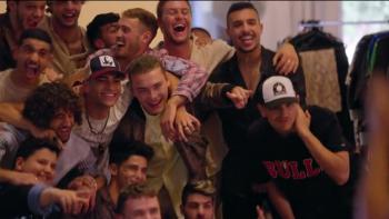 A group of young men pose, smile, and laugh for a photoshoot. They were sportswear and trendy streetwear.