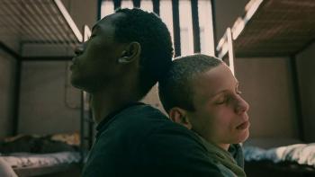 Havtamo Frada and Guy Manster lean against each other back-to-back. Havtamo wears a black t shirt, Guy wears a green hoodie.