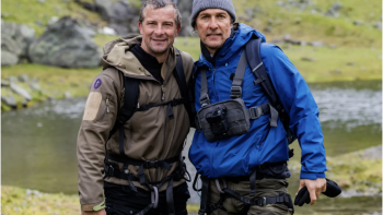Bear Grylls is Running Wild TV show screenshot: Grylls and Matthew McConaughey stand in full rain gear with their arms around each other in Norway.