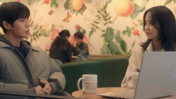 Between Steps TV show screenshot 2: Park Min-Jae talks to Im Yu-jin at table with coffee mug and laptop.