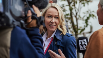 Billionaire Island screenshot 1: Julie Lange talks to reporters. 