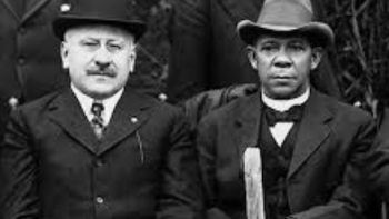 Black and Jewish America TV show screenshot 3: Julius Rosenwals and Booker T. Washington sitting together wearing suits and hats.
