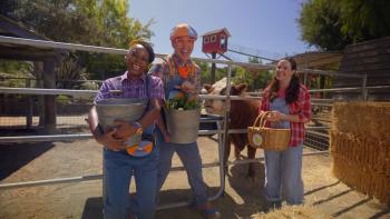 Blippi's Job Show screenshot 3: Meekah and Blippi outside at a farm, holding buckets to feed the cow behind them. Next to them, Farmer holds a basket.