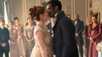 Bridgerton Season 3 TV show screenshot 1: Francesca and John kiss at the center of a drawing room as Bridgerton family members applaud behind them