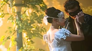 Bridgerton Season 4 TV show screenshot 3: Sophie and Benedict embrace while wearing masks in front of glowing yellow flowers