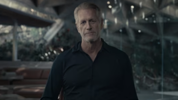 Bring Me the Beauties TV show screenshot 1: Older Hoyt Richards in a dark shirt sitting in a modern, dimly lit interior space.