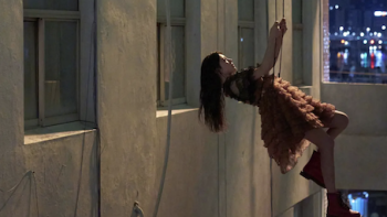 Can This Love Be Translated? TV show screenshot 2: Cha Mu-hee dressed in pink dress as Do Ra-mi hangs from wire next to building window.