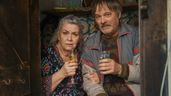 Can You Keep a Secret? TV show screenshot: An older couple peers out a window together holding drinks.