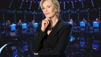 Celebrity Weakest Link TV show screenshot 2: Blonde, middle aged host Jane Lynch wears a black suit with her fist under her chin