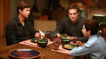 Champions TV Series: Two men sit at a dining table with a teen boy.