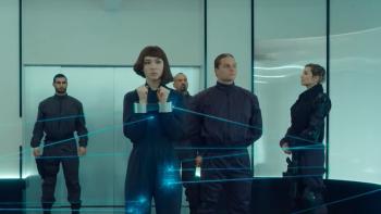 Matilda De Angelis holds her handcuffed wrists up. She is surrounded by guards. Angelis wears a dark blue jumpsuit.
