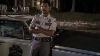 Crystal Lake TV show screenshot 2: Police chief Levon Books stands by patrol car at night, arms crossed, serious expression.