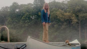 Crystal Lake TV show screenshot 3: Pamela Voorhees standing on a docked canoe, surrounded by misty trees.