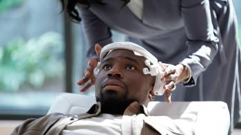 Demascus TV show screenshot 1: Okieriete Onaodowan reclines in a white leather chair. A pair of hands lift a white headset off his forehead.