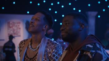 Demascus TV show screenshot 2: Caleb Eberhardt and Okieriete Onaodowan stand in art gallery. Eberhardt wears a fishnet top and a sequin blazer.