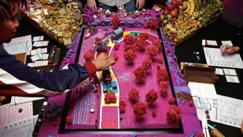 Dimension 20 TV show screenshot 3: Overhead shot of the game table for the season "A Crown of Candy" shows pink mini-trees and a colorful path