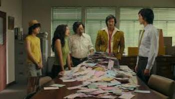 Doctor Climax TV show screenshot: Four Thai men and a Thai woman stand around a table piled with male.