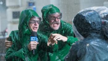 DTF St. Louis TV show screenshot 2: Clark and Floyd wear green rain slickers and Clark holds a microphone as they report from a fierce storm