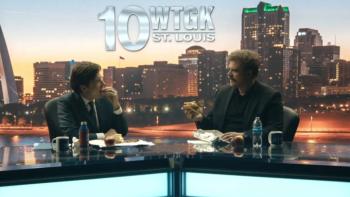 DTF St. Louis TV show screenshot 3: Clark and Floyd sit together at a news desk, each eating a sandwich, as their channel chyron appears on screen