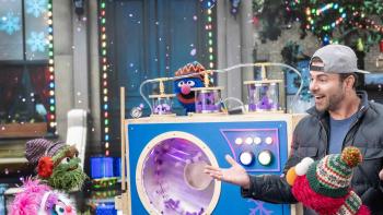 Elmo & Mark Rober's Merry Giftmas TV: Abby watches with happiness as Mark Rober and Elmo show her gift — a snow machine!