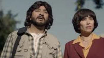 screenshot 1: Chuy and Camila watch as buildings fall. 