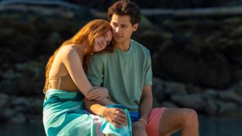 Every Year After TV show screenshot 2: In bathing suits, Percy and Sam sit together on a dock by the lake; Percy puts her head on Sam's shoulder