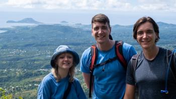 Fantastic Friends TV show screenshot: Three White adults are standing on a ledge looking down on a town.