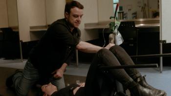 Follow This Series: A man leans over a woman on her back with legs bent, holding her knees down. 